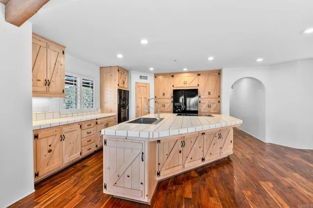 a view of an empty room with wooden floor and a ceiling fan