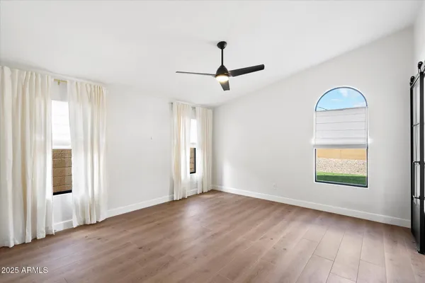 a view of empty room with wooden floor and fan