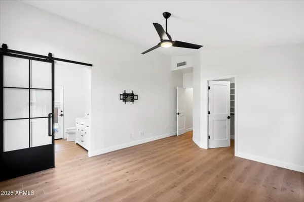 a view of empty room with wooden floor and fan