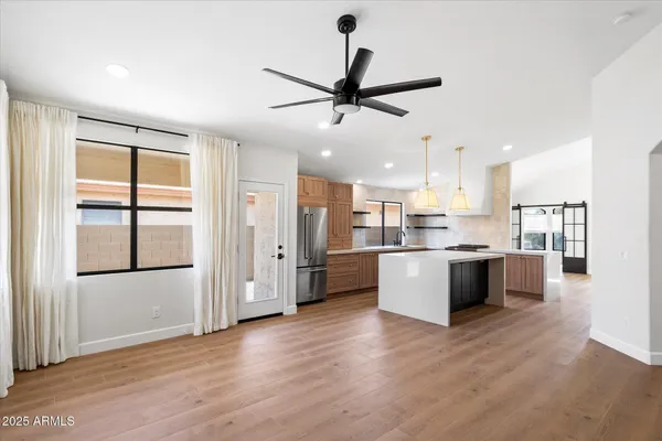 a large kitchen with a refrigerator a sink dishwasher with a large window and wooden floor