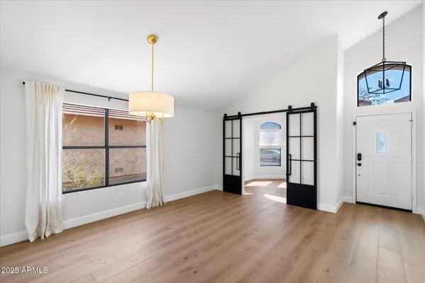 a view of an empty room with window and wooden floor