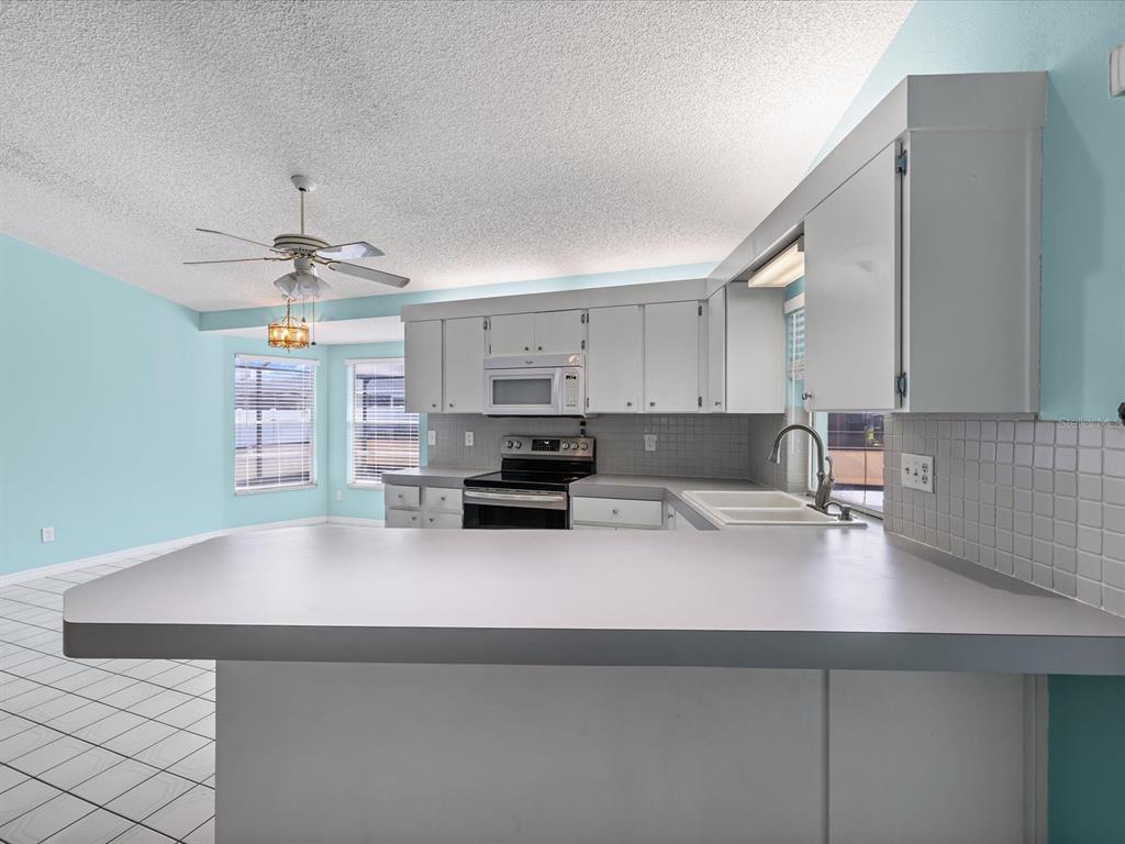 5853 Redhawk Drive New Port Richey, FL 34655 - Photo 11 of 38 a kitchen with kitchen island a sink white cabinets and appliances