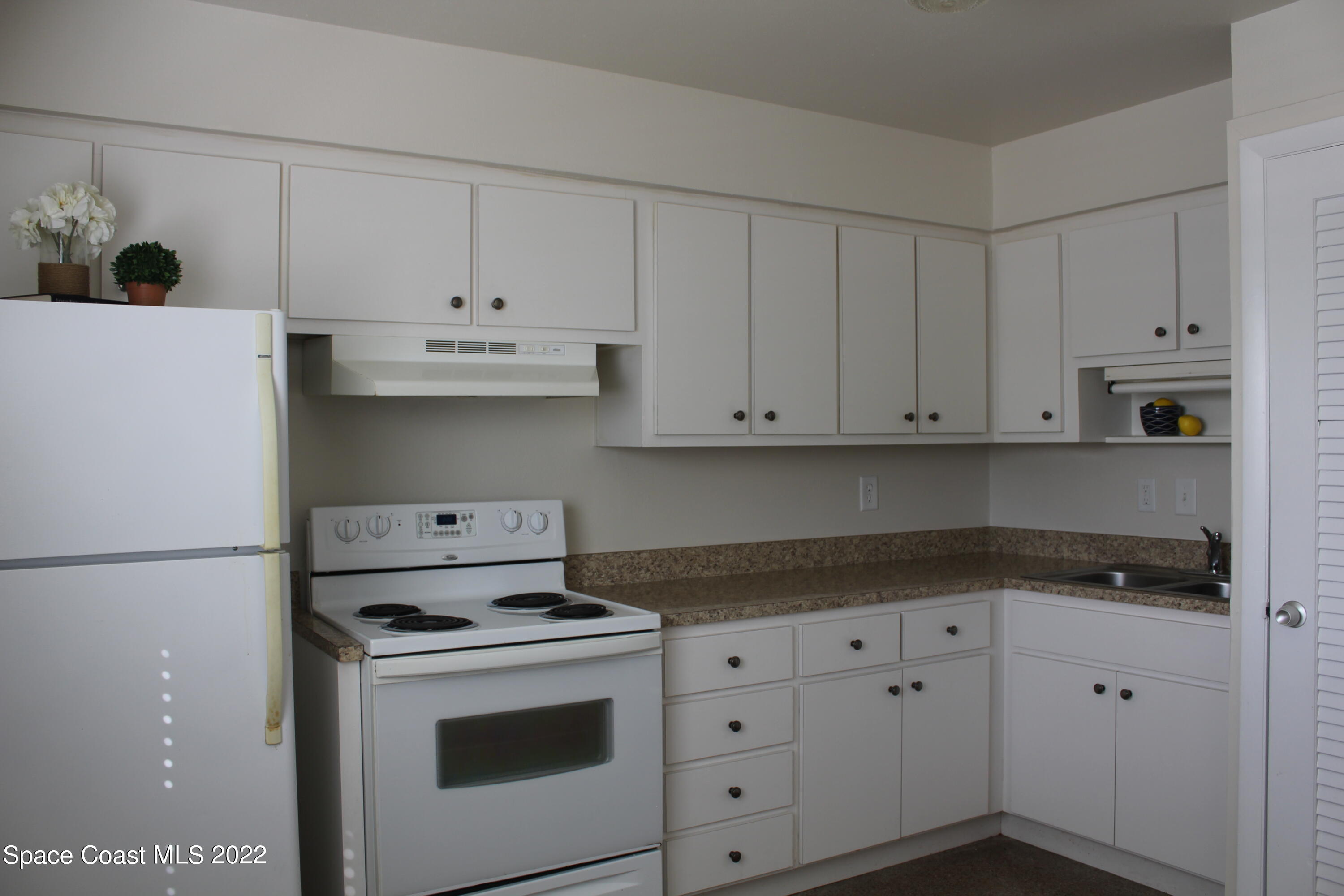 651 Palm Drive, Unit C2 Satellite Beach, FL 32937 - Photo 10 of 13 a kitchen with white cabinets and white appliances