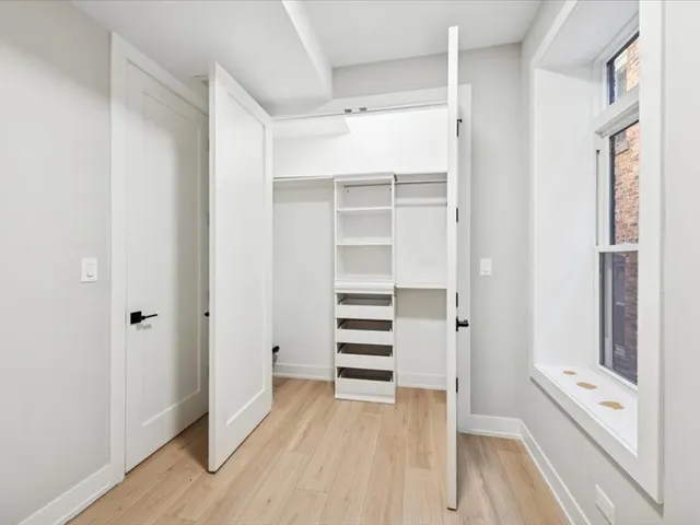 a view of a walk in closet with wooden floor and closet