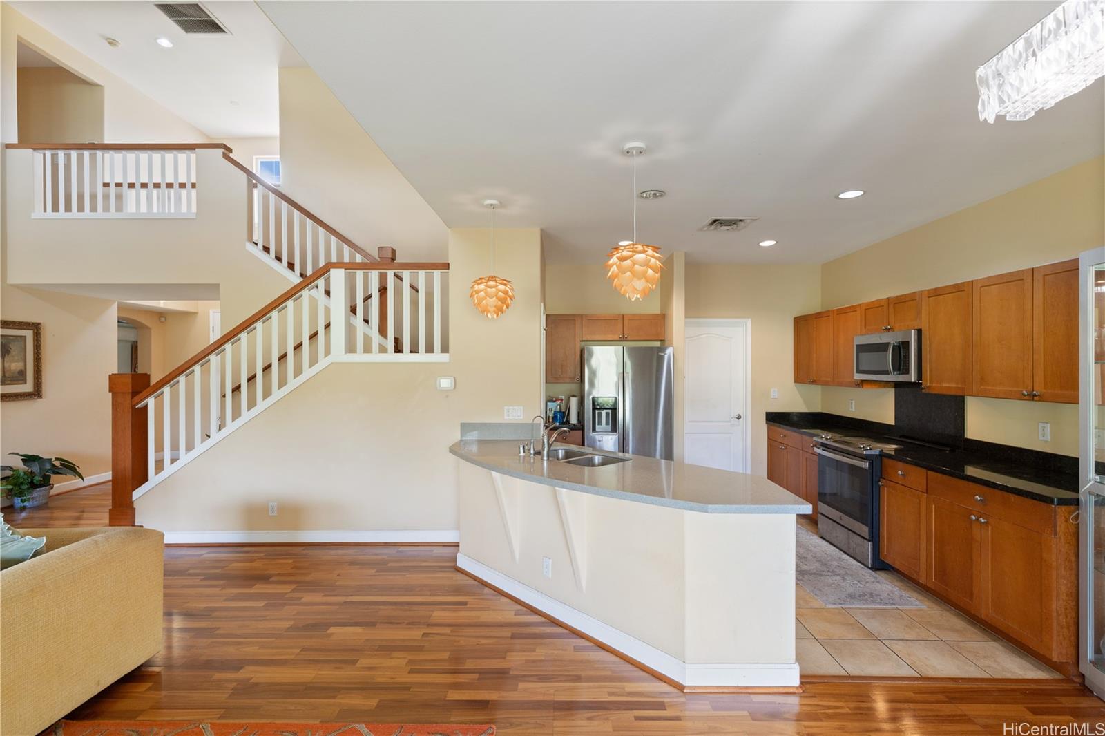 92-1015 Koio Drive, Unit S52 Kapolei, HI 96707 - Photo 16 of 18 a kitchen with stainless steel appliances kitchen island granite countertop a sink a stove top oven and a dining table
