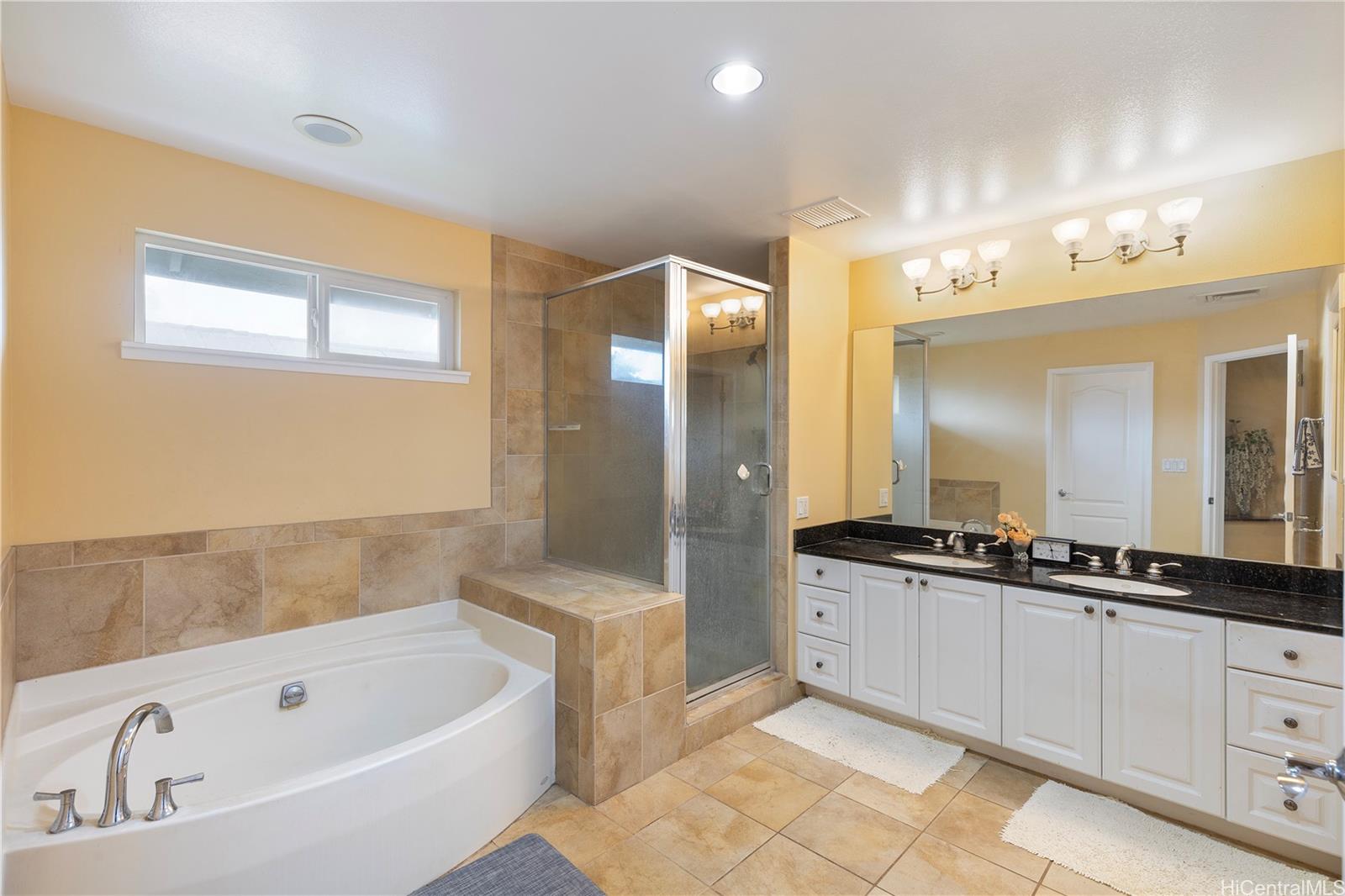 92-1015 Koio Drive, Unit S52 Kapolei, HI 96707 - Photo 17 of 18 a bathroom with a bathtub a double vanity sink and mirror