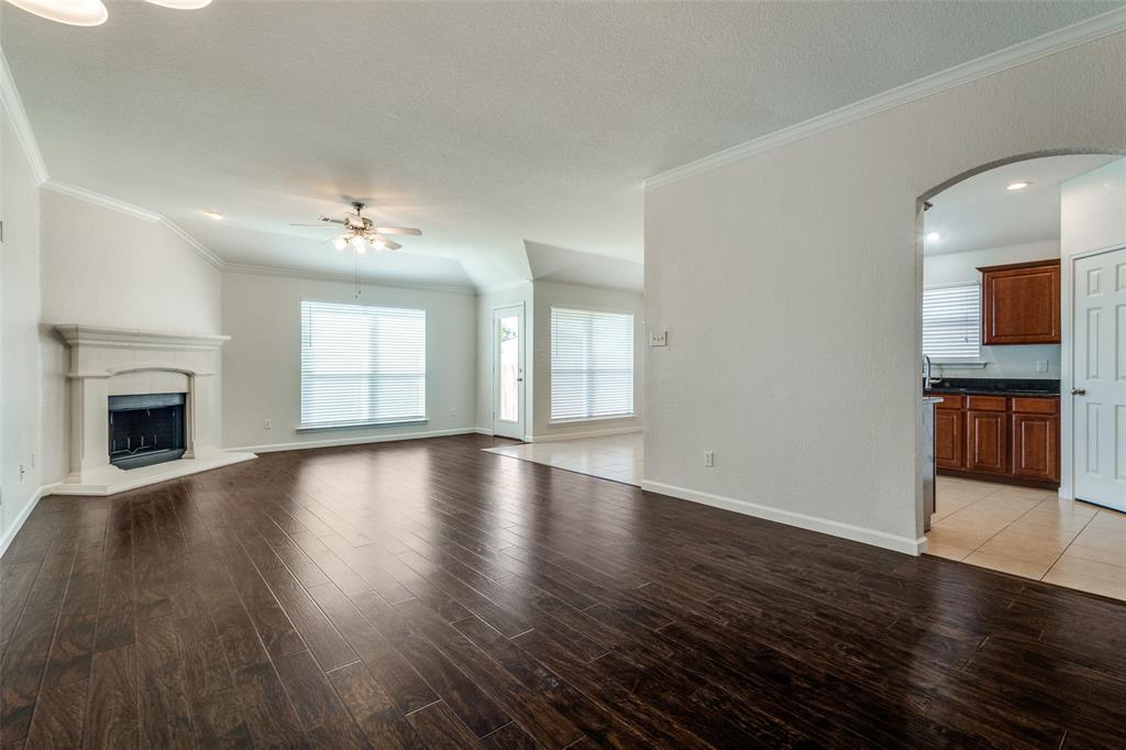 1257 Barrel Run Fort Worth, TX 76052 - Photo 7 of 26 Spacious living area featuring wood-finish flooring, a corner fireplace with a white mantel, and vaulted ceilings with crown molding