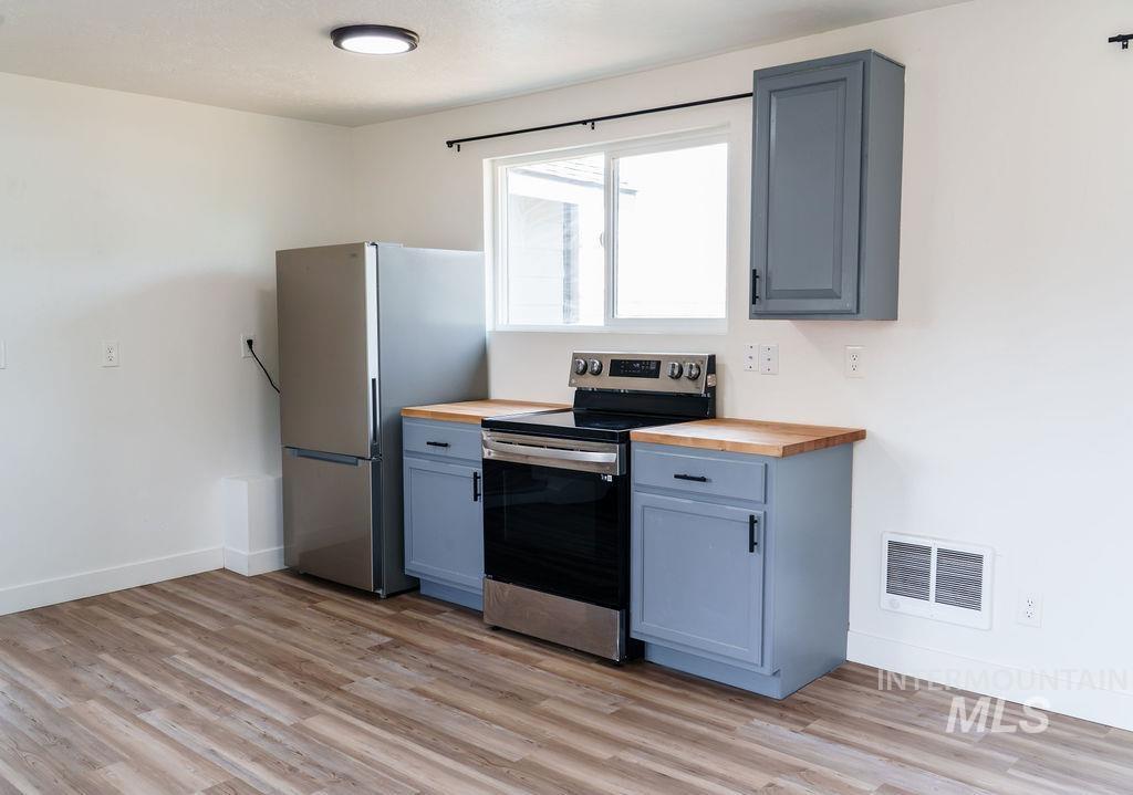 933 South Mill Road Emmett, ID 83617 - Photo 5 of 19 Kitchenette featuring wood-finish flooring, light gray cabinetry, and a full suite of stainless steel appliances