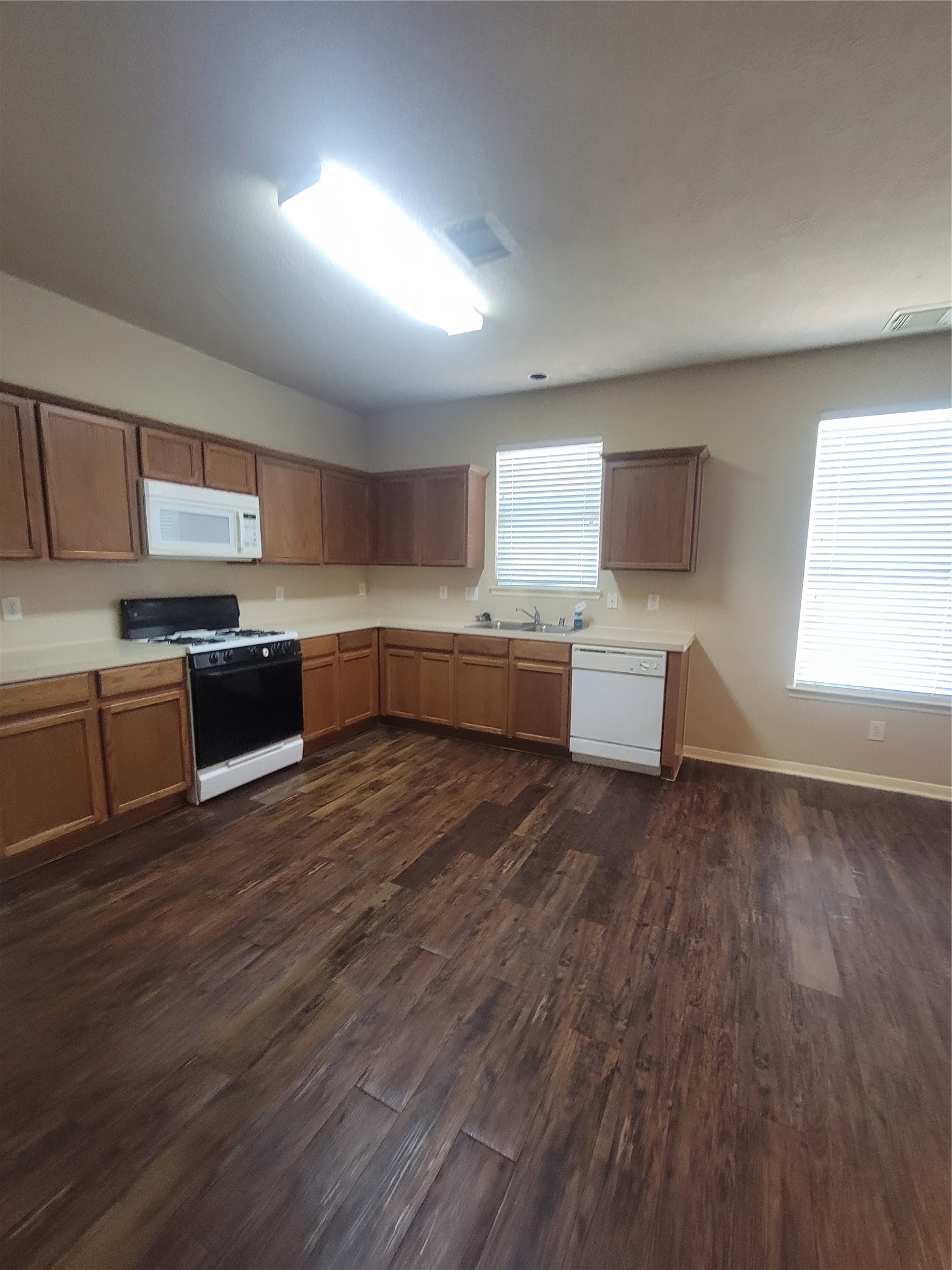 3110 Clover Ranch Circle Katy, TX 77494 - Photo 6 of 28 a large kitchen with stainless steel appliances a large counter top a sink a stove a refrigerator with grey cabinets and wooden floor