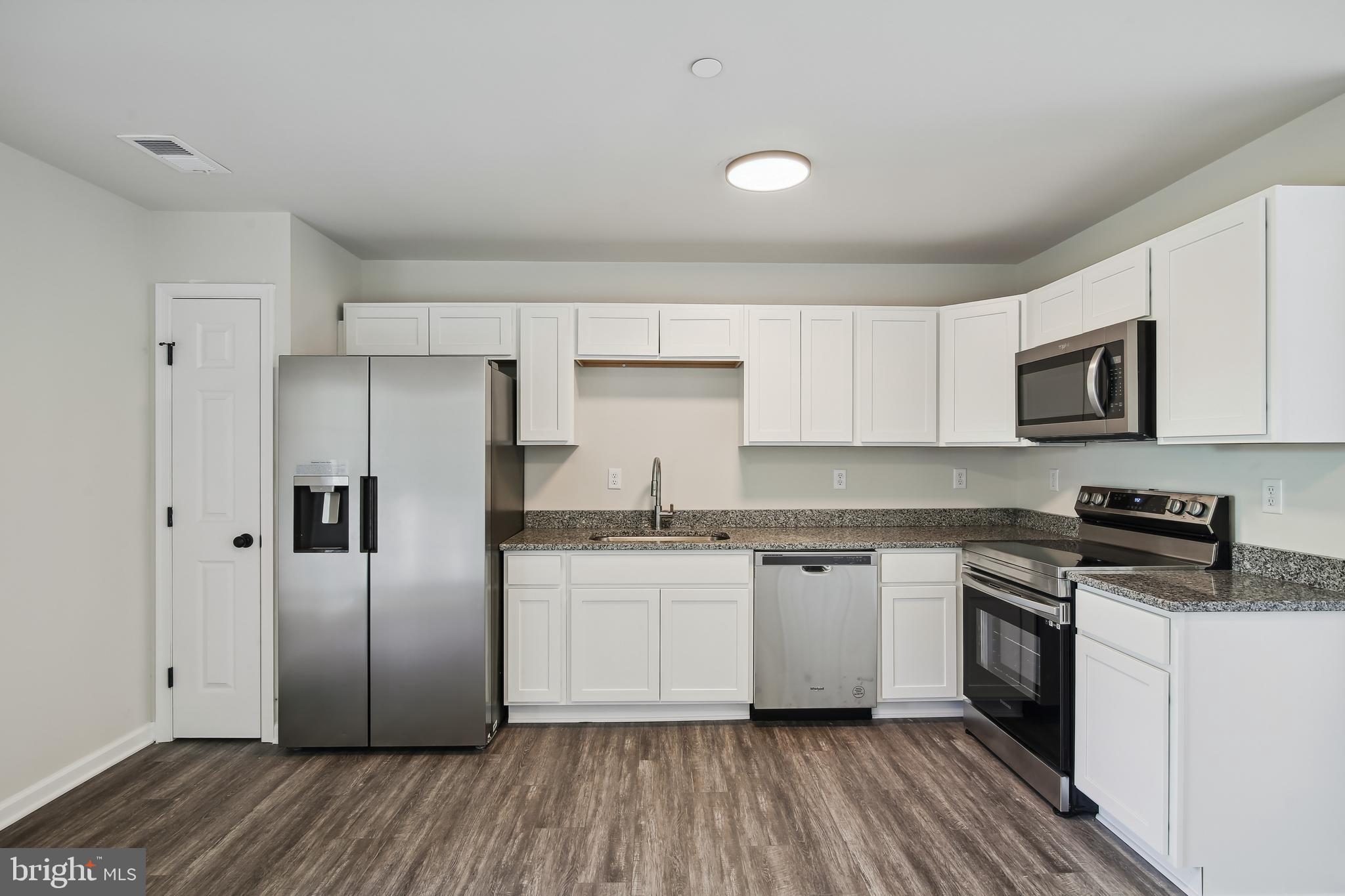 101 Metcalf Road Chestertown, MD 21620 - Photo 8 of 26 a kitchen with granite countertop a refrigerator stove a sink and white cabinets with wooden floor