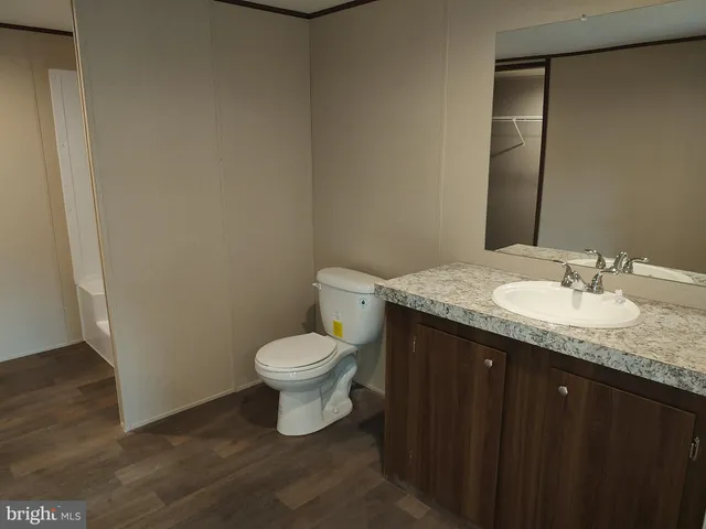 a bathroom with a granite countertop sink toilet and mirror