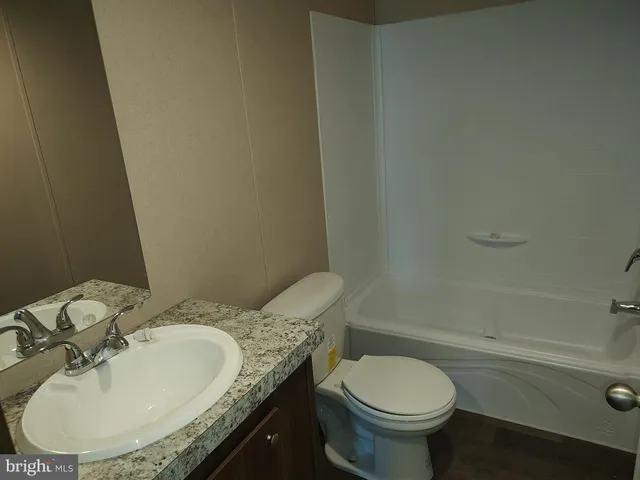 a bathroom with a granite countertop toilet a sink and mirror