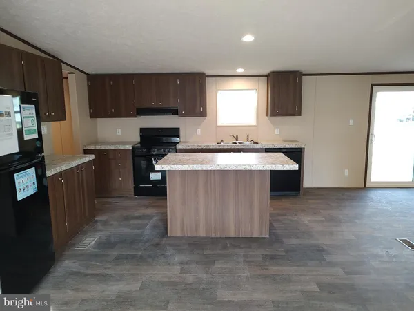 a kitchen with kitchen island granite countertop a sink stove and refrigerator