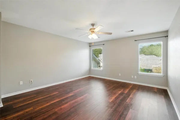 a view of an empty room and wooden floor a ceiling fan