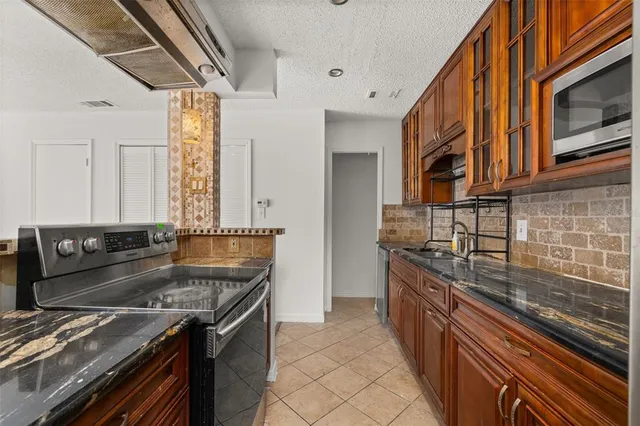a kitchen with granite countertop a sink stove and cabinets