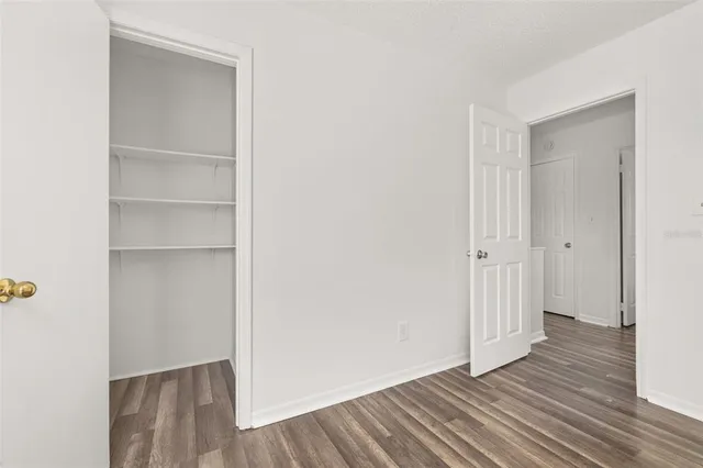 a view of an empty room with wooden floor and closet