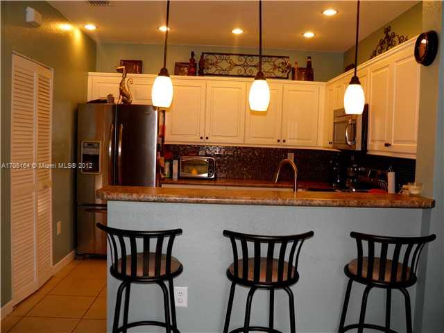 9237 Southwest 227th Street, Unit 12 Cutler Bay, FL 33190 - Photo 5 of 9 a kitchen with a table chairs and a refrigerator