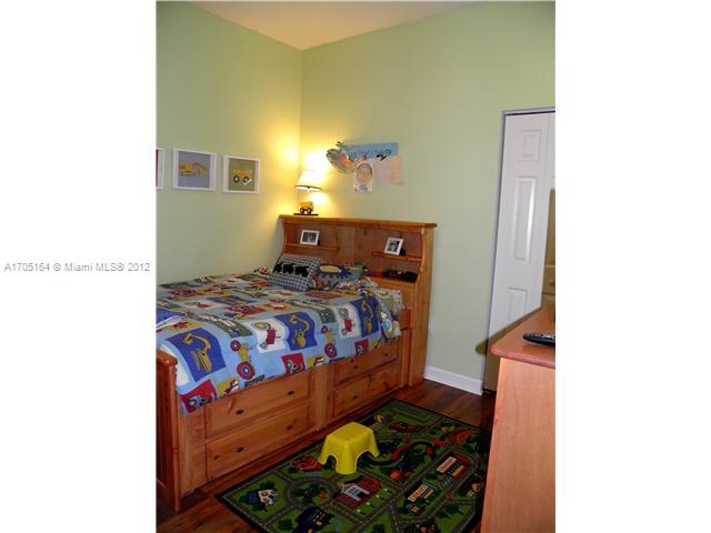9237 Southwest 227th Street, Unit 12 Cutler Bay, FL 33190 - Photo 7 of 9 a bedroom with a bed and a painting on the wall