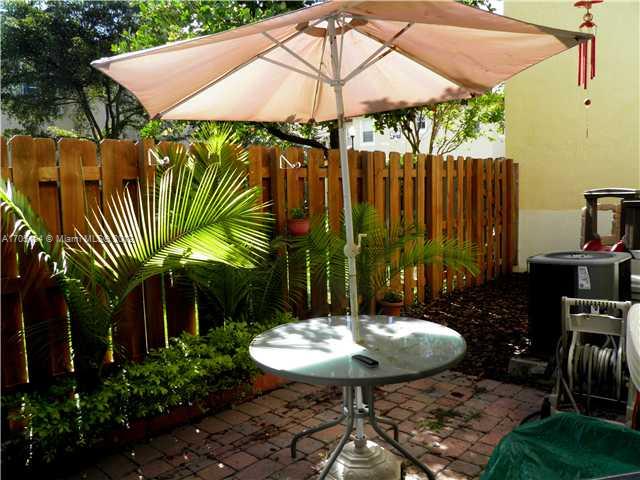 9237 Southwest 227th Street, Unit 12 Cutler Bay, FL 33190 - Photo 8 of 9 a view of a backyard with table and chairs under an umbrella