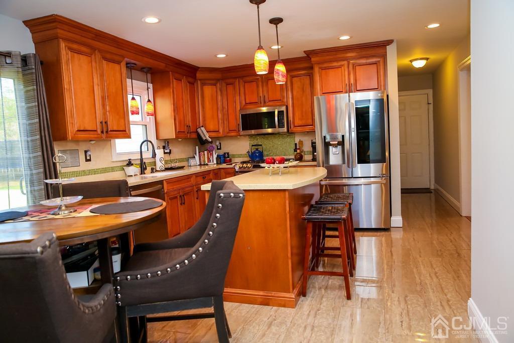 65 Tower Road Edison, NJ 08820 - Photo 6 of 11 a kitchen with a table chairs refrigerator and microwave