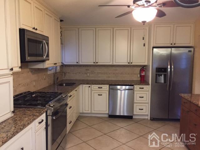 65 Tower Road Edison, NJ 08820 - Photo 9 of 11 a kitchen with stainless steel appliances granite countertop a stove a sink and a microwave