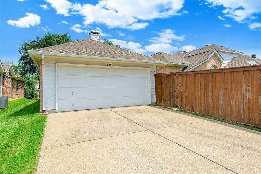 1404 Ranch Hill Drive Irving, TX 75063 - Photo 31 of 31 Attached garage featuring a white door, concrete driveway, and a shingle roof