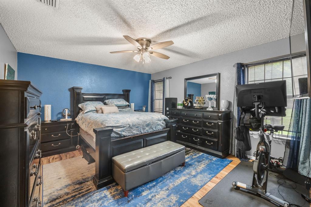 916 Danforth Place Arlington, TX 76017 - Photo 16 of 30 Spacious room featuring wood-finish flooring, a textured accent wall, and a ceiling fan with integrated lighting