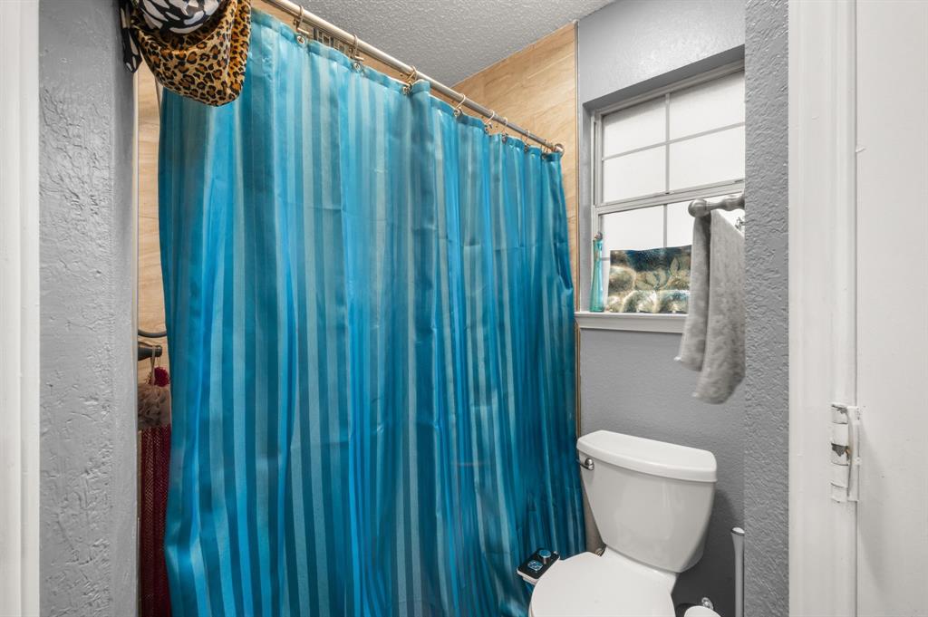 916 Danforth Place Arlington, TX 76017 - Photo 18 of 30 Bathroom featuring a white toilet, transom window, and tiled shower surround