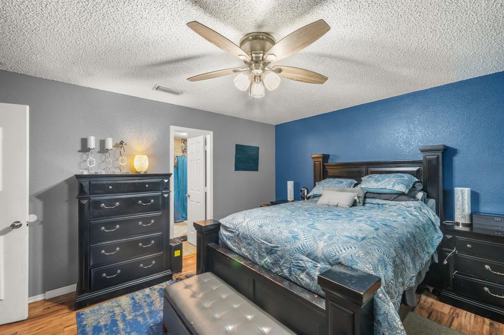 916 Danforth Place Arlington, TX 76017 - Photo 19 of 30 Bedroom featuring wood-finish flooring, a textured blue accent wall, and a ceiling fan with integrated lighting