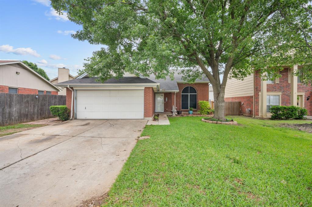 916 Danforth Place Arlington, TX 76017 - Photo 2 of 30 Brick facade residence featuring a two-car garage, mature front yard tree, arched front window, concrete driveway, and established perimeter fencing
