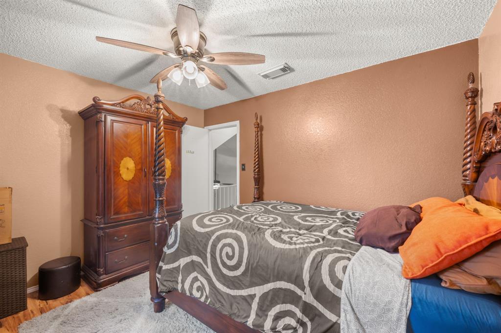 916 Danforth Place Arlington, TX 76017 - Photo 25 of 30 Room featuring wood-finish flooring, a ceiling fan with light fixture, textured walls, and a visible doorway