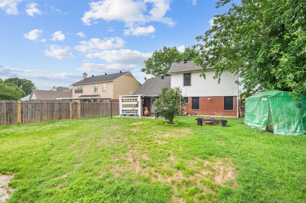 916 Danforth Place Arlington, TX 76017 - Photo 29 of 30 Expansive backyard featuring a privacy fence, mature trees, and a covered patio area
