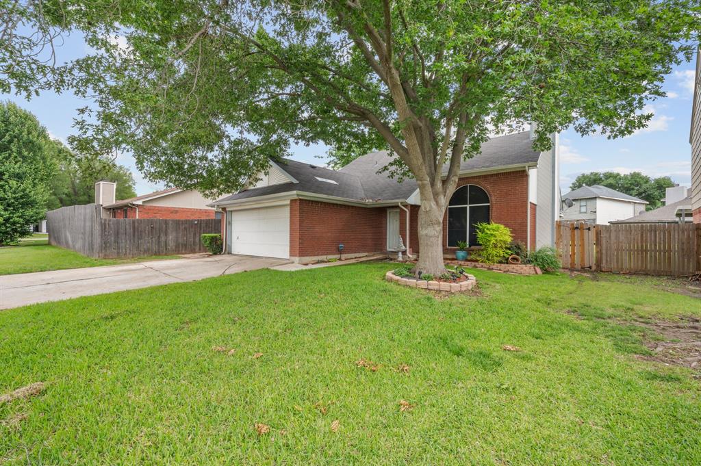 916 Danforth Place Arlington, TX 76017 - Photo 3 of 30 Brick exterior residence featuring a prominent mature tree, an arched window, a two-car garage, and a wood privacy fence