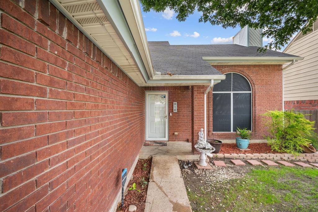 916 Danforth Place Arlington, TX 76017 - Photo 5 of 30 Brick exterior with a white entry door, an arched window, and a gabled roofline