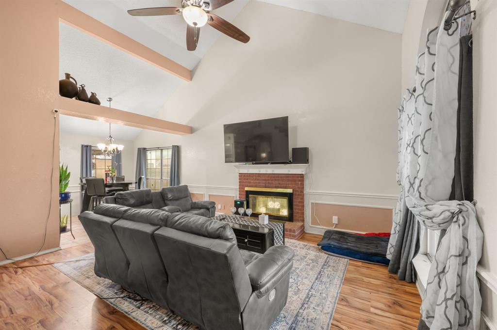 916 Danforth Place Arlington, TX 76017 - Photo 7 of 30 Spacious living area featuring vaulted ceilings, exposed beams, wood-finish flooring, a brick fireplace, and an open concept layout