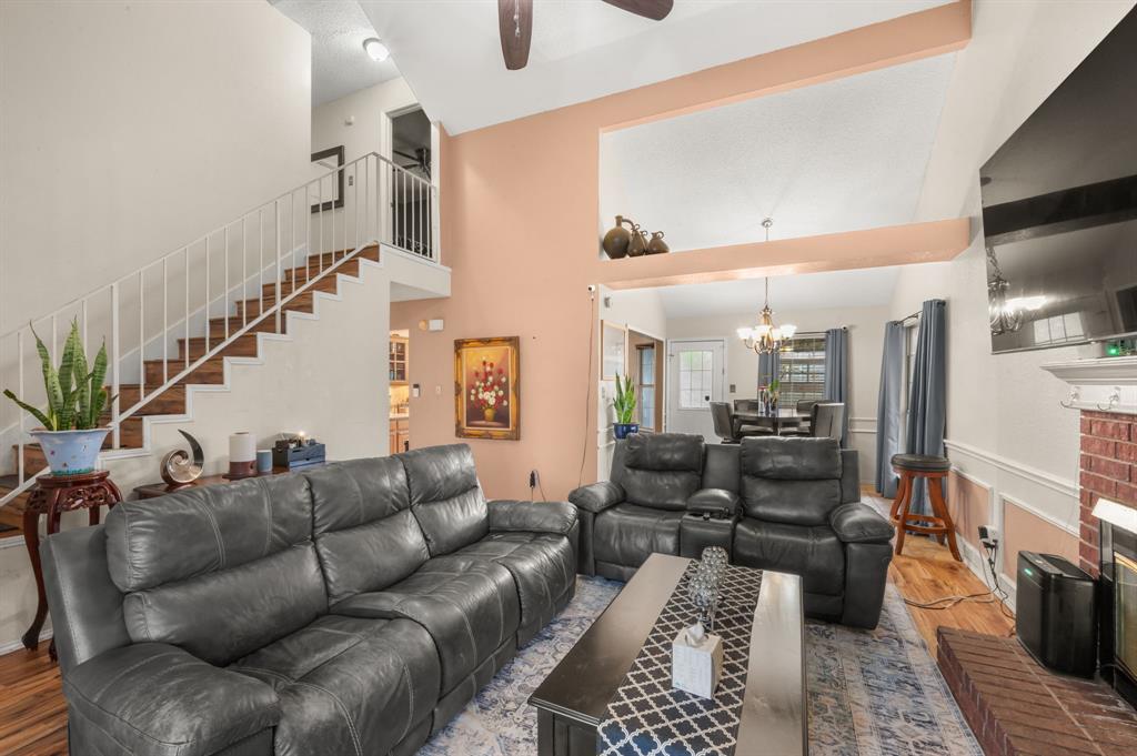 916 Danforth Place Arlington, TX 76017 - Photo 8 of 30 Vaulted ceilings highlighting exposed beams, a wood-finish staircase with white railings, and a brick fireplace