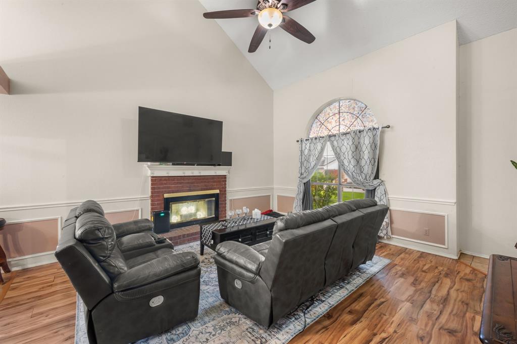 916 Danforth Place Arlington, TX 76017 - Photo 9 of 30 Living room with vaulted ceiling, wood-finish flooring, and a brick fireplace with a white mantel