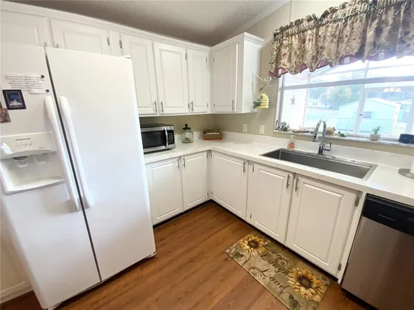 a kitchen with a sink a refrigerator a window and cabinets
