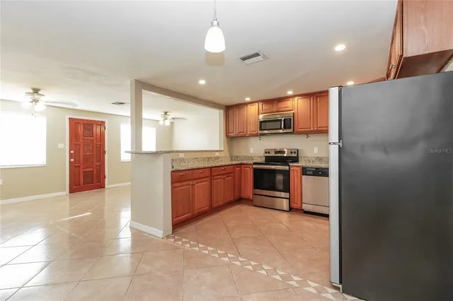 a large kitchen with stainless steel appliances kitchen island granite countertop a refrigerator and a stove top oven