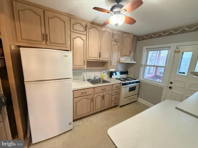 a kitchen with granite countertop a refrigerator a sink dishwasher a stove and white cabinets with wooden floor