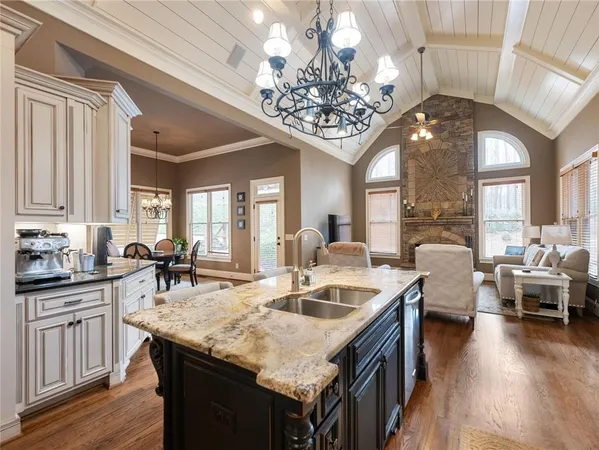 a large white kitchen with granite countertop a sink dishwasher a dining table and chairs with wooden floor