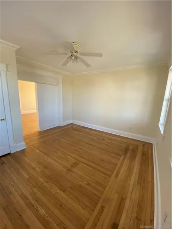 an empty room with wooden floor fan and windows