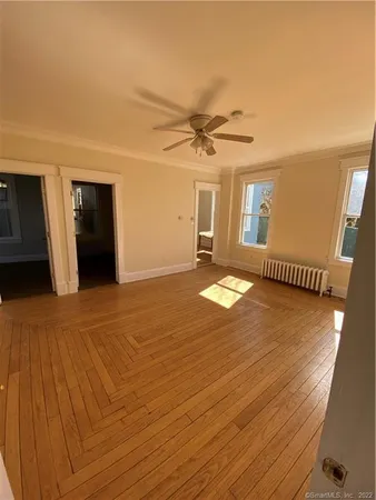 a view of an empty room with window and wooden floor