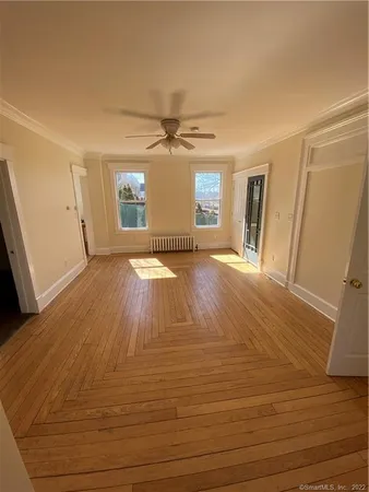 a view of an empty room with window and wooden floor