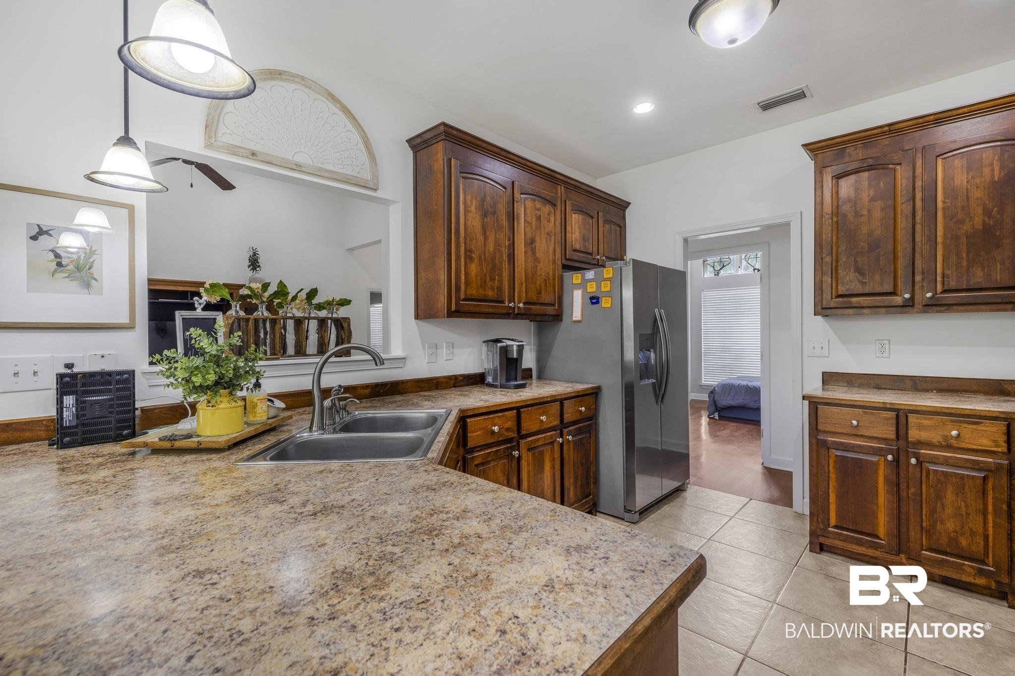35814 Delvan Lane Bay Minette, AL 36507 - Photo 18 of 53 Kitchen featuring a double basin stainless steel sink with a gooseneck faucet, light granite-style countertops, and rich wood cabinetry