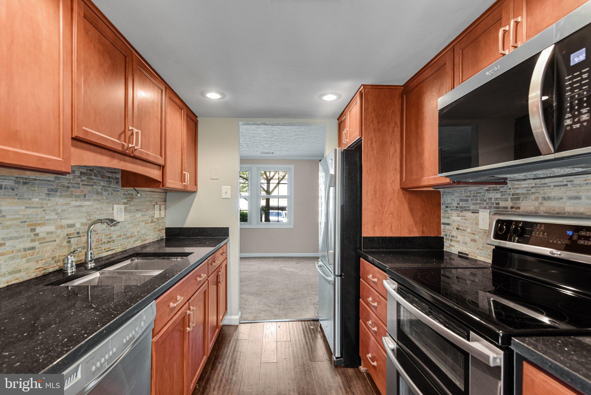 8339 Bark Tree Court Springfield, VA 22153 - Photo 5 of 23 a kitchen with stainless steel appliances granite countertop a stove a sink and a microwave