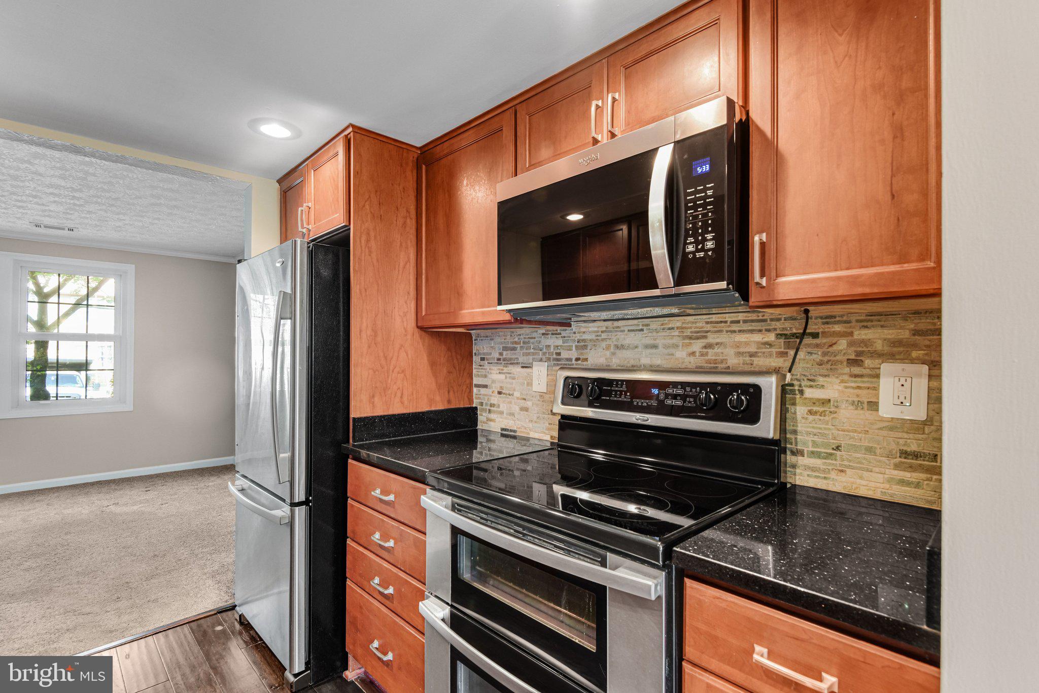 8339 Bark Tree Court Springfield, VA 22153 - Photo 6 of 23 a kitchen with granite countertop a stove and a microwave