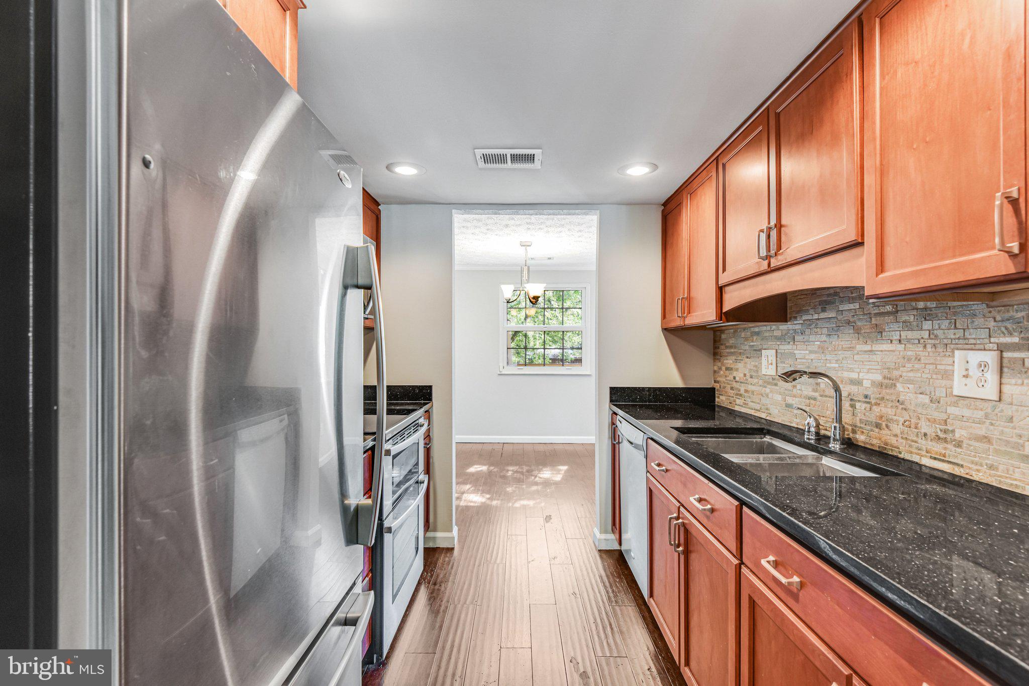 8339 Bark Tree Court Springfield, VA 22153 - Photo 8 of 23 a kitchen with stainless steel appliances granite countertop a refrigerator a sink dishwasher a stove and white countertops with wooden floor