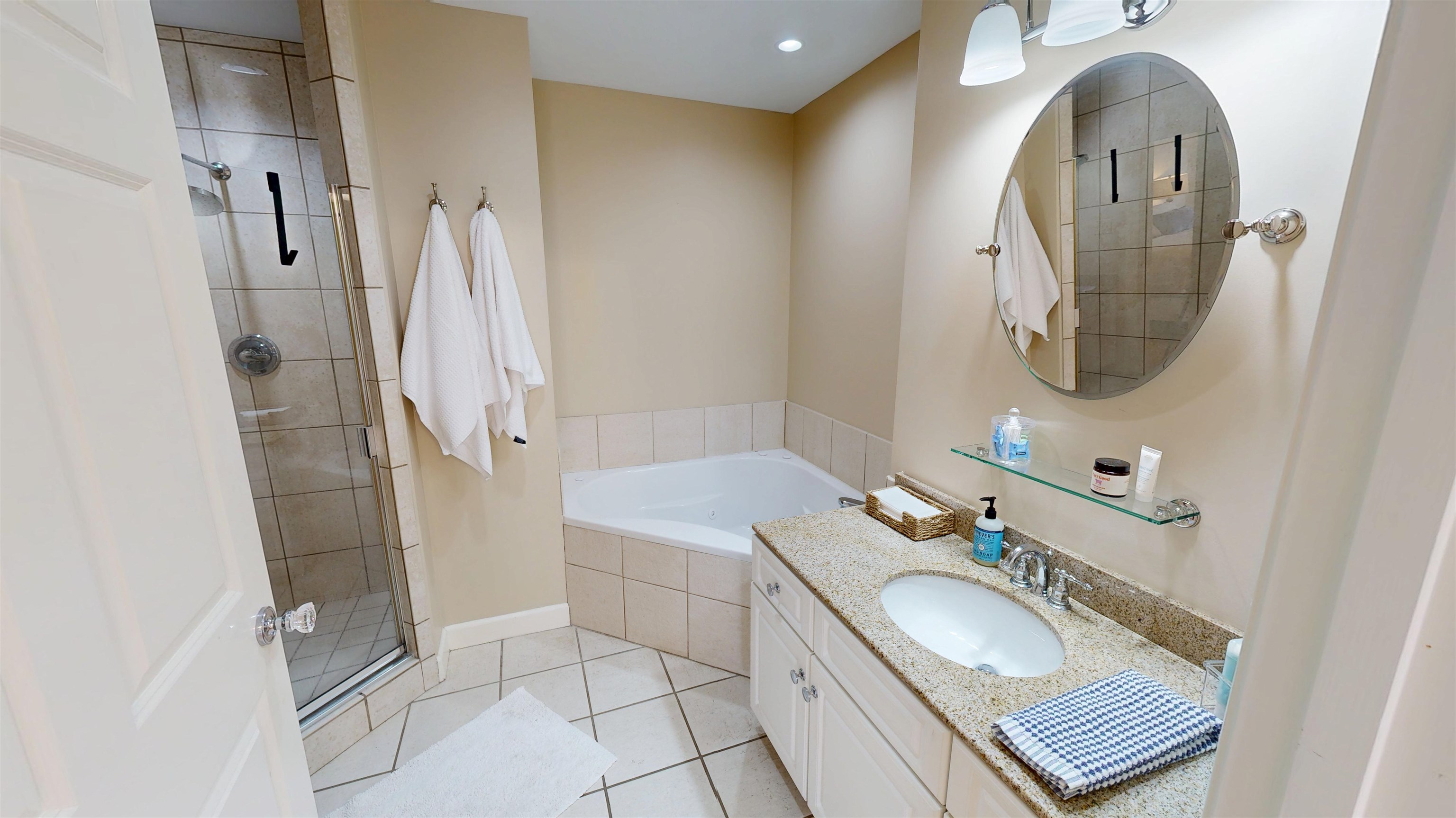 325 Cr 380 L-103 Road, Unit L103 Iuka, MS 38852 - Photo 23 of 40 Bathroom featuring a glass-enclosed shower with tile surround, a built-in tub, a vanity with a light-toned countertop, an oval mirror, and ceramic tile flooring