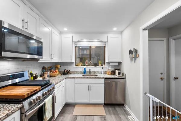 a kitchen with stainless steel appliances granite countertop a sink stove and cabinets